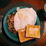 a table with a plate full of breakfast foods and a cup of coffee