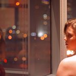 Girl staring at a reflection of herself in the window.