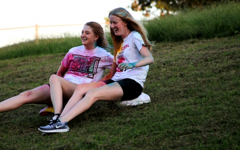 Two female students sliding down the hill on ice together