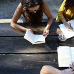 Three students studying on a picnic bench together