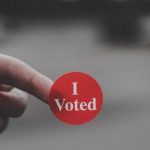A person holding an "I Voted" sticker