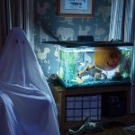 A man with a white sheet sitting in a room