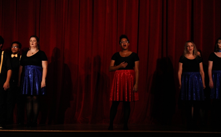 A woman singing in front of a red curtain