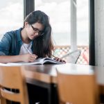 Student studying at a desk with a book open.