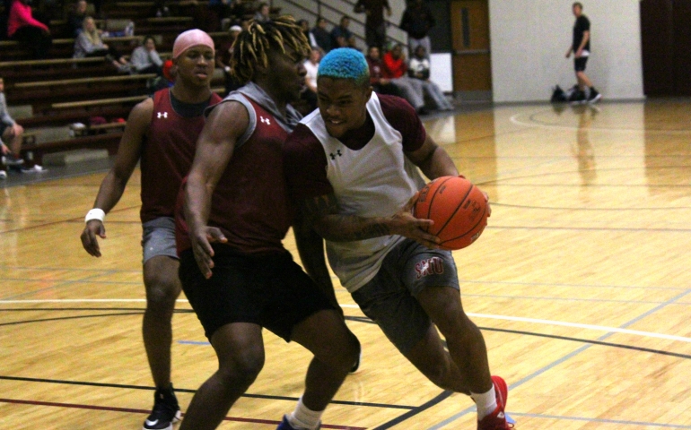 A student defends the basket on a drive