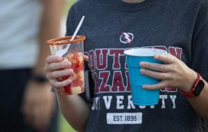 A student holding a drink and a cup of fruits