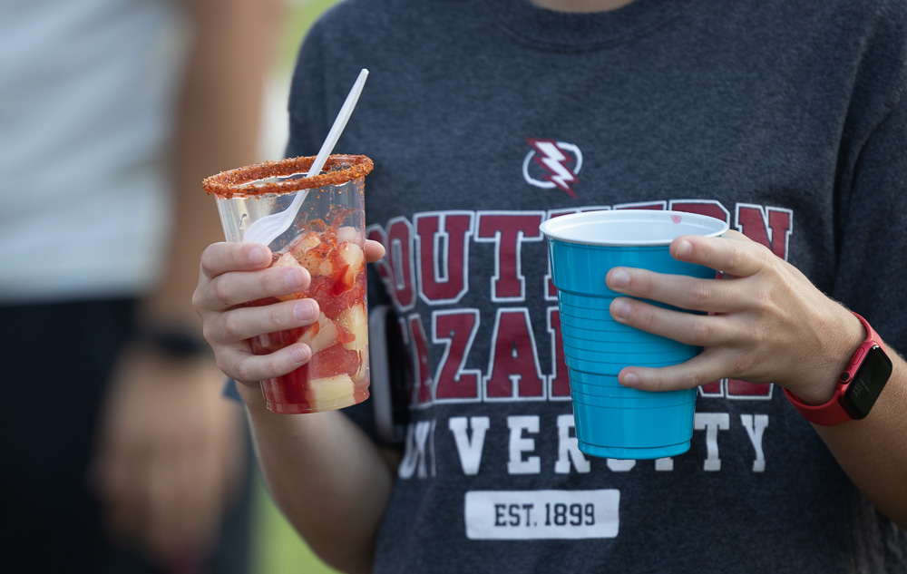 A student holding a drink and a cup of fruits