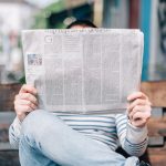 A man on a bench holding a newspaper