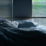 Messy sheets on a bed by windows